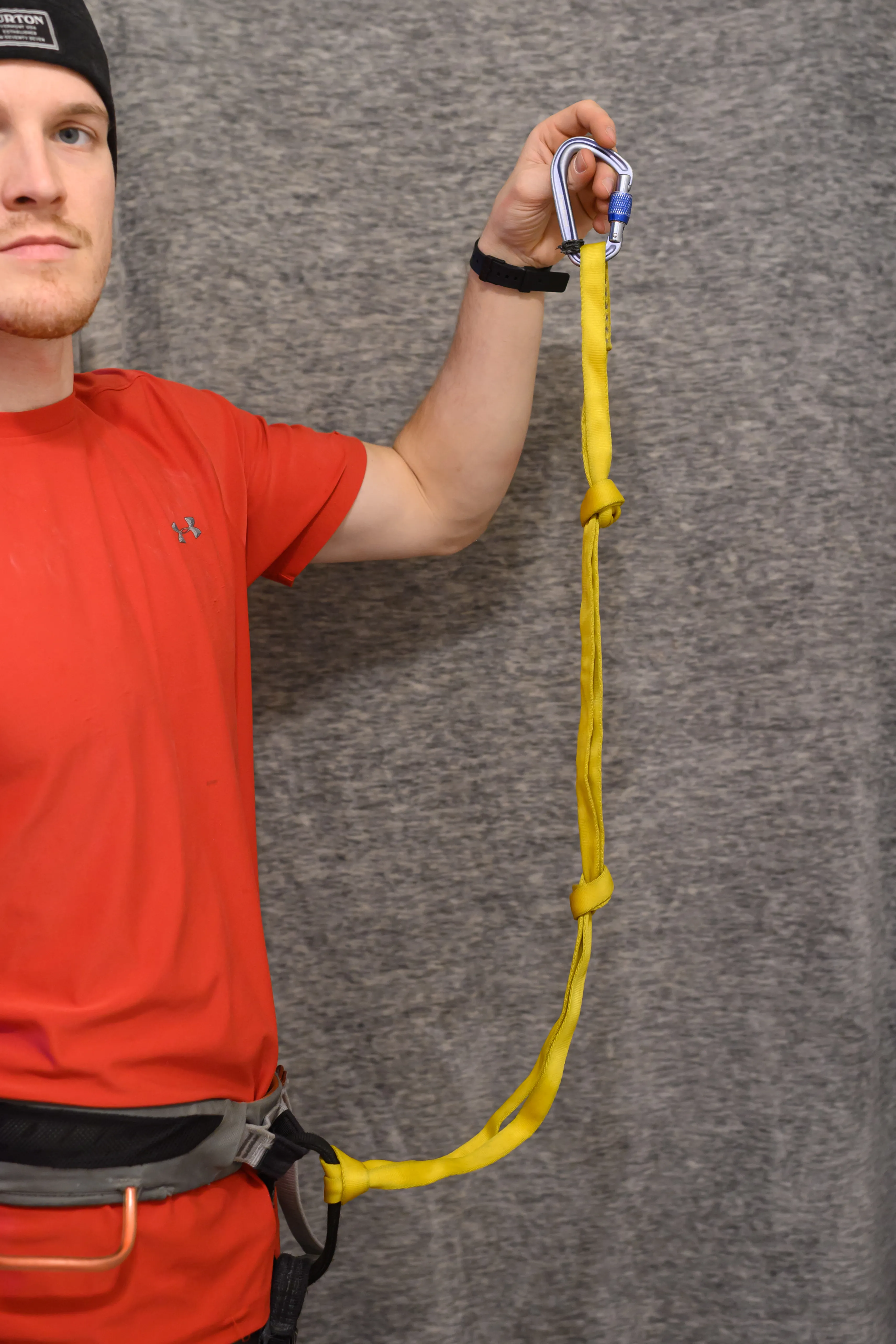 Photo of nylon double length sling girth hitched through belay loop with multiple knots tied in it.