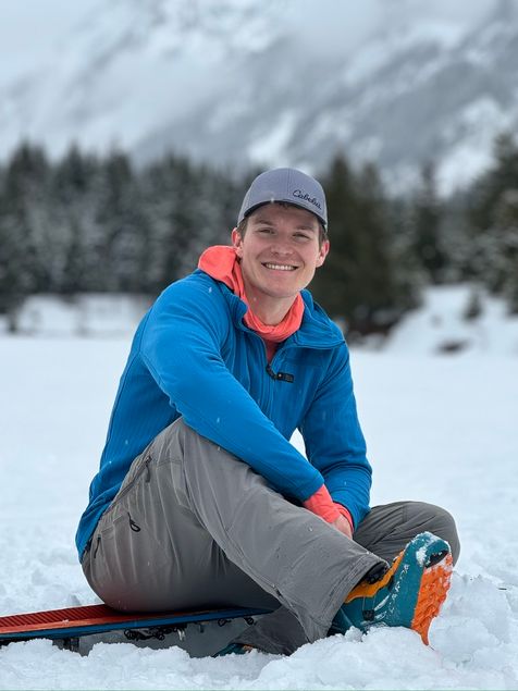 Tom Skoog holding a pair of skis in the mountains